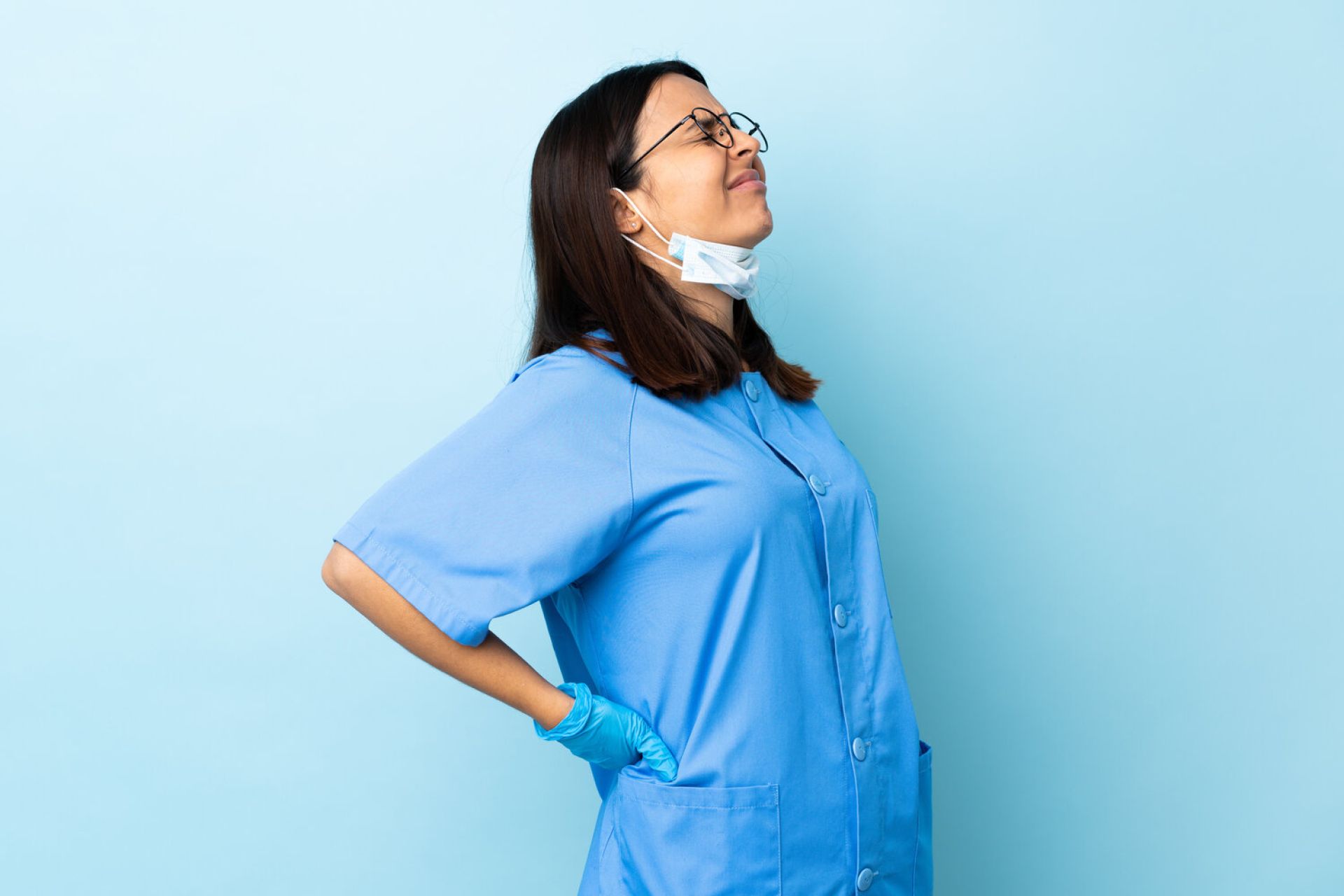 Surgeon woman over isolated blue background suffering from backache for having made an effort Importance of Ergonomics in the Medical Workplace